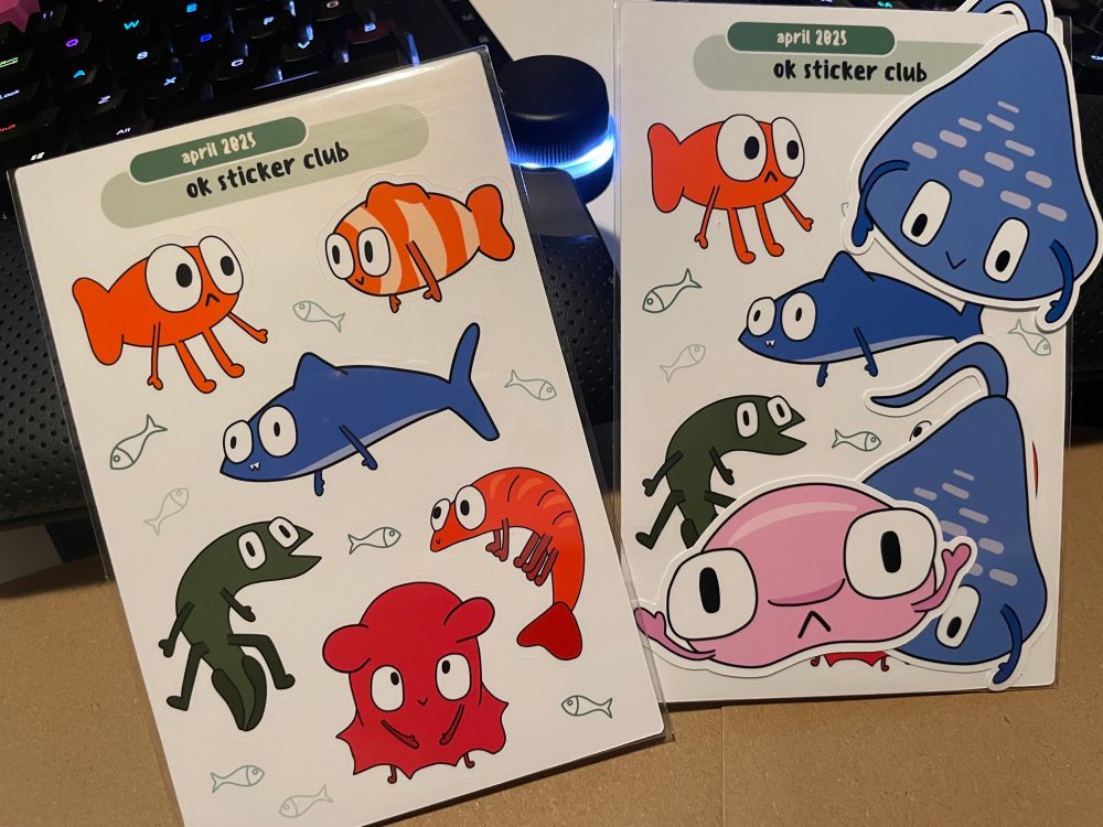 ok sticker club sheets with simple drawings of the following animals with big eyes and skinny arms: orange goldfish, clownfish, shark, eel, dumbo octopus, and shrimp. Die cut stickers of a stingray and a blobfish with big eyes and skinny arms