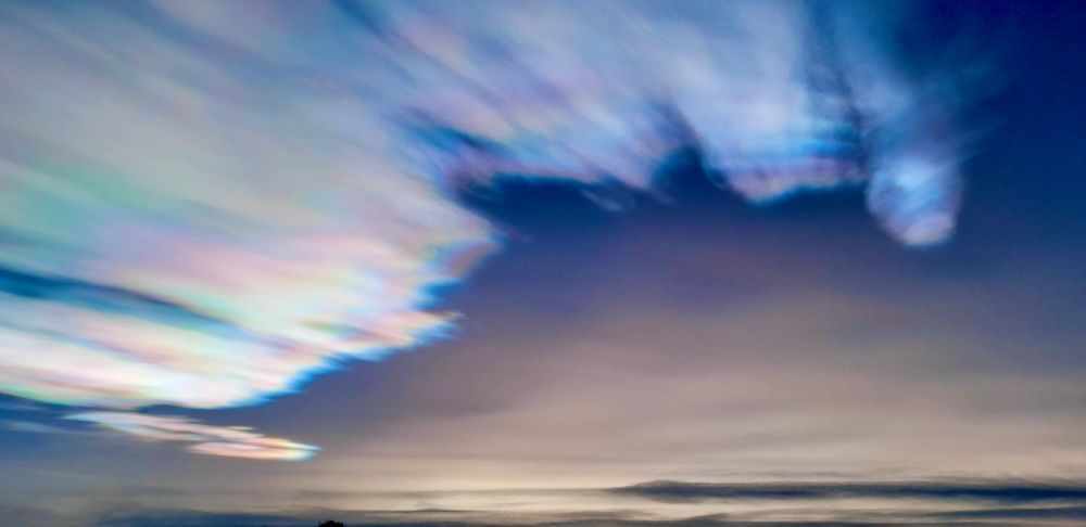 A photograph of clouds in the sky. A rainbow-colored light surrounds the clouds