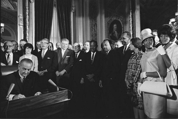 Lyndon Johnson signing into law the Voting Rights Act of 1965. Martin Luther King is among those visible in the background.