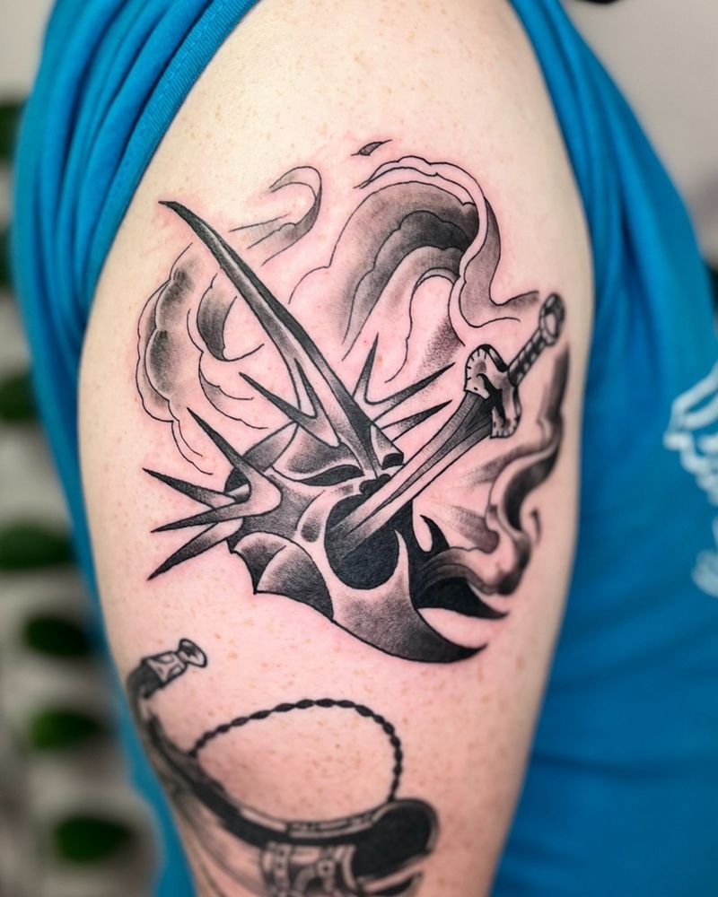 A black and gray tattoo of the witch king of Angmar’s helmet being stabbed by Eowyn’s sword
