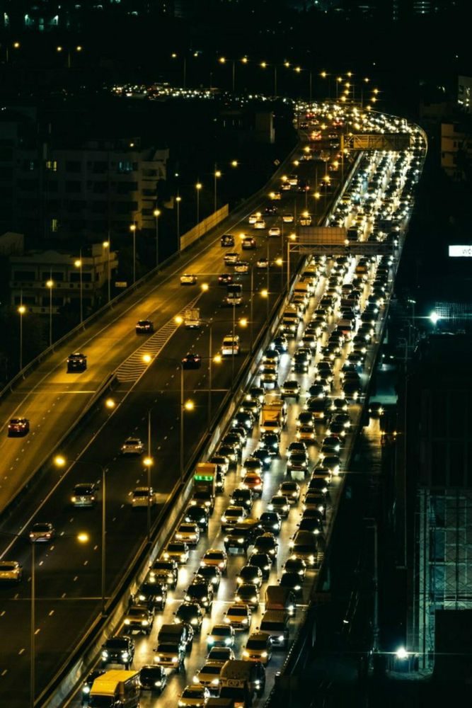 An overview of nighttime urban traffic, with four lanes bumper to bumper.