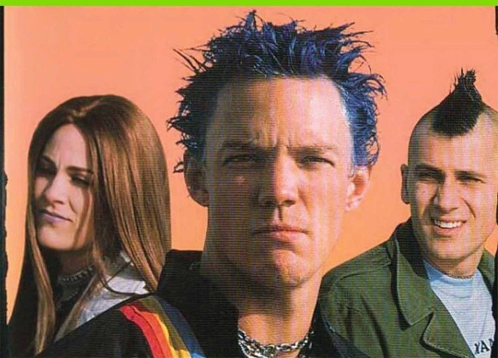 A woman with long light brown hair, a man with messy blue dyed hair, a smiling man with a dark brown mohawk. 