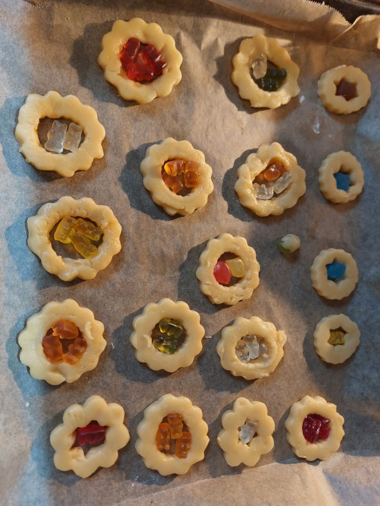 Ausgestochene Kekse, in der Mitte Löcher, darin je 2-3 Gummibären