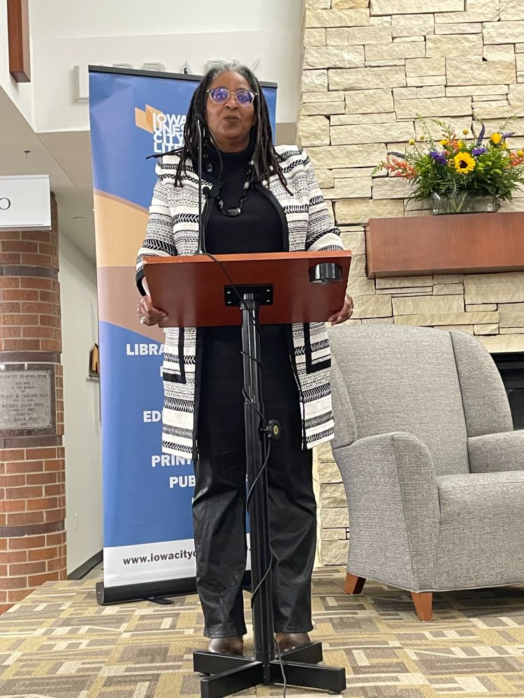 A woman stands behind a lectern on a stage. 
