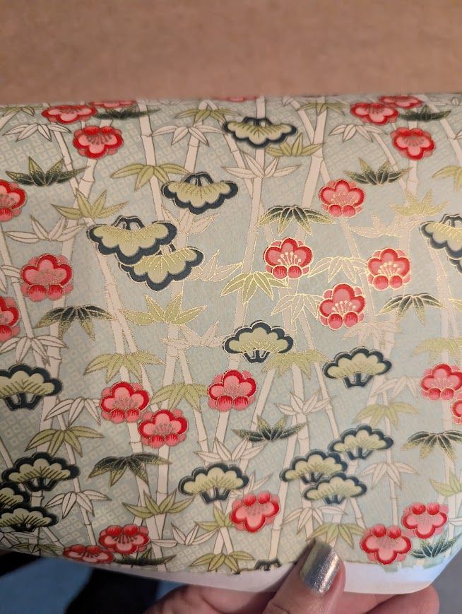 pale green paper with gold accents in a pattern of bamboo stalks and red flowers
