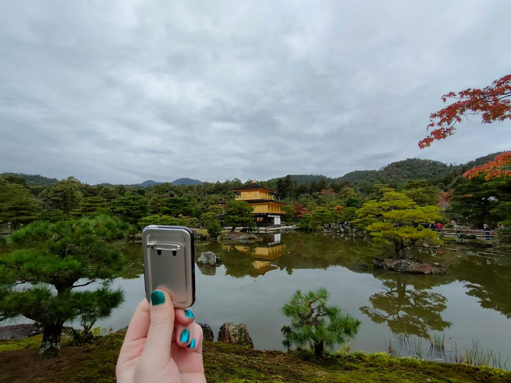 金閣寺にサンポのスクエア缶バッジを見せてあげている（1枚目はサンポがカメラ目線だったのに対し、この2枚目の写真ではサンポは金閣寺の方を向いている）。