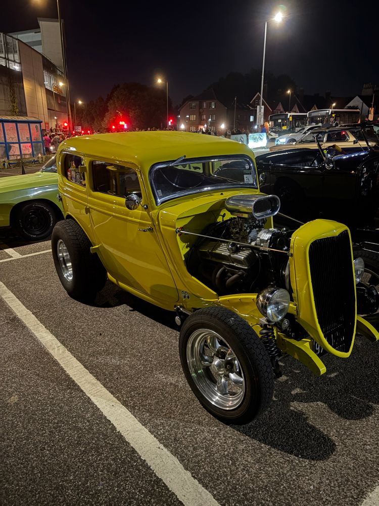 Very yellow car with its engine exposed - like a 1930s style cab but with a very very modern engine. 