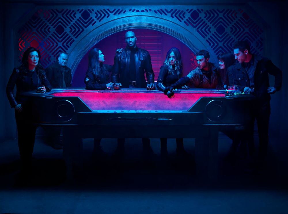 Agents of SHIELD S6 promotional photo featuring the cast around a gambling table of some sort, last supper style. Overall blue with pink highlights. Cool as hell.