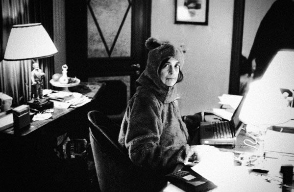 Photo of Susan Sontag wearing bear costume, sitting at the desk. Made by Anne Leibovitz. 