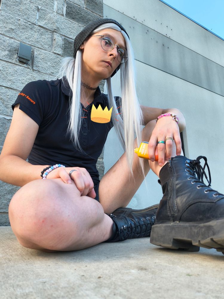 Amy sitting outside'a work 
she's wearing her black work shirt and black shorts and black boots, she has a yellow vape in her left hand, which is sitting on top of her right hand on her knee
she's got a black choker, jewelery and eyeshadow
she has rings on her middle and ring finger on her left hand, two bracelets on the right a pink bracelet on the left 
she hittin dat shit