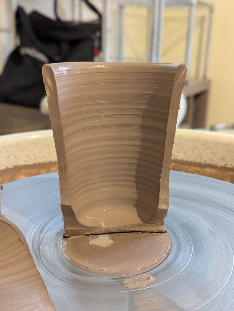 wheel thrown clay in a cup shape, split down the middle to inspect the walls.