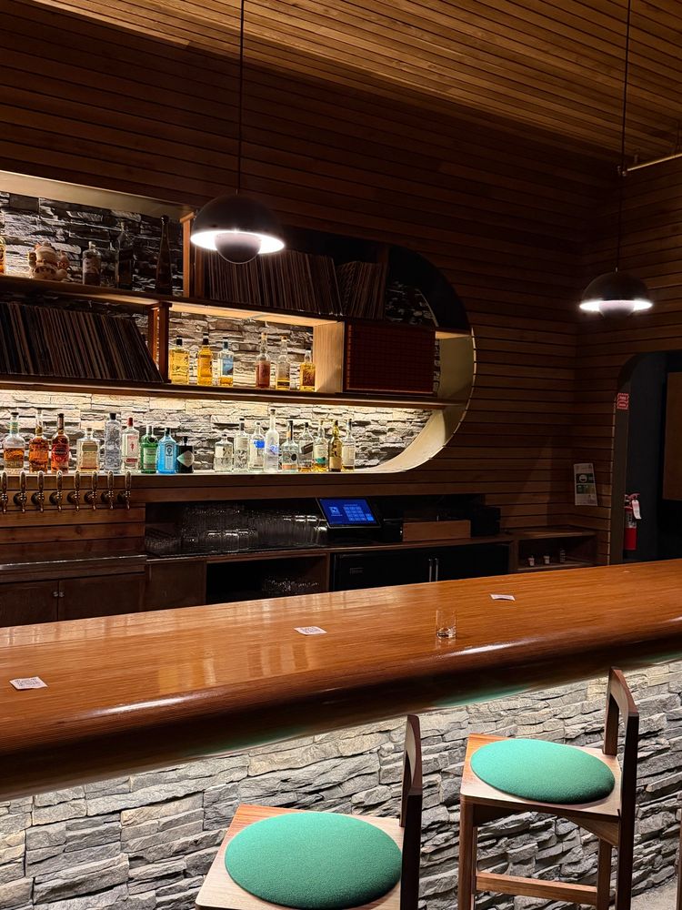 Teakwood cocktail bar with uplighting and green felted benches.