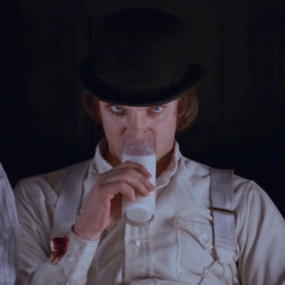 a man wearing a top hat is drinking milk from a glass