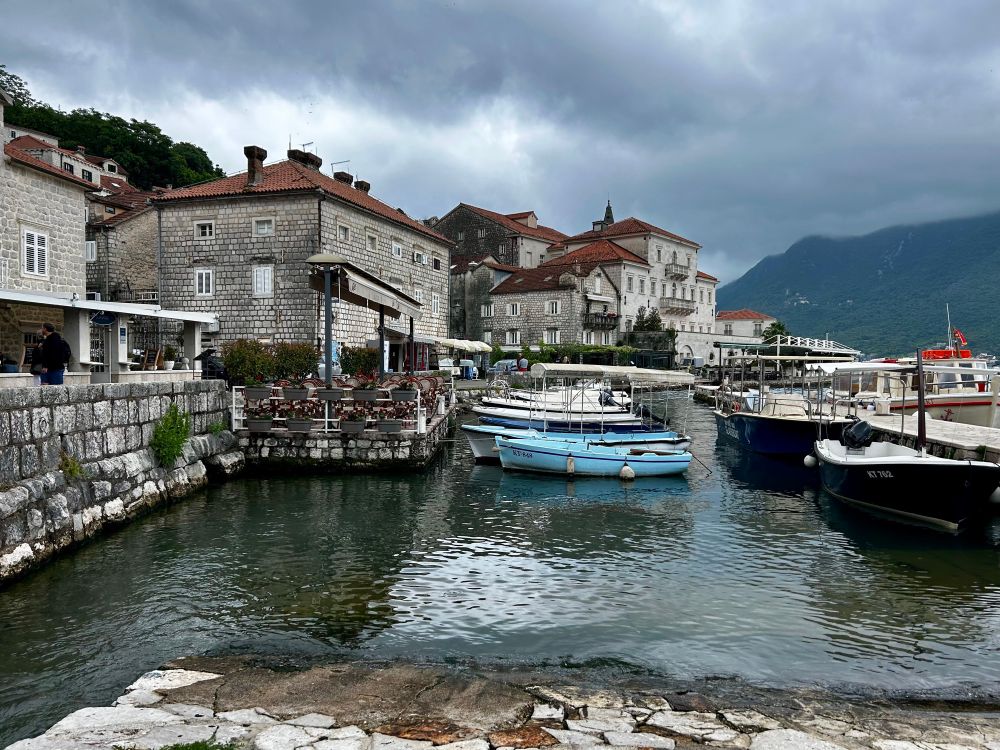 Charming houses along the shore, and boats tied up in the water in Kotor, Montenegro, a beautiful Baltic location.