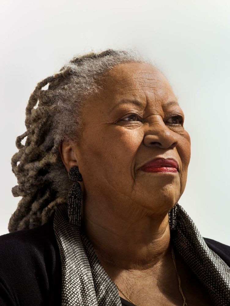 Photo featuring the head and shoulders of a Black woman with grey dreads facing slight right against a white background 