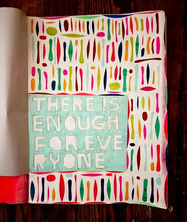 Photo of the painted page of a sjetch book with colourful shapes and hand created text 'there is enough for everyone'