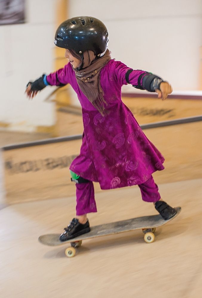 Photo of a girl in a purple dress skateboarding