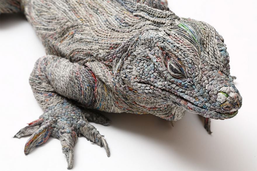 Close-up of a sculpture of a grey lizard type of creature, showing the upper half facing slight right