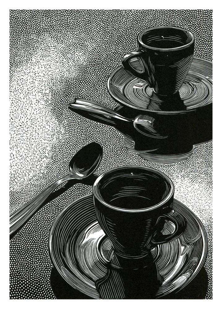 Print in black and white featuring a view looking slightly down on two cups and saucers with teaspoons on a surfsce