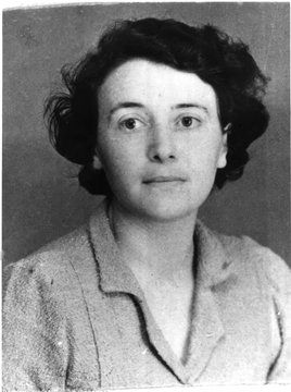 Monochrome photograph featuring the head and shoulders of a white woman facing forwards with dark wavey hair wearing a blouse