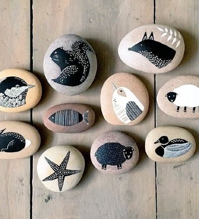 Photo of ten pebbles grouped together viewed from above each stone has a painted image on it of an animal,bird or fish including a sheep,duck and rabbit 