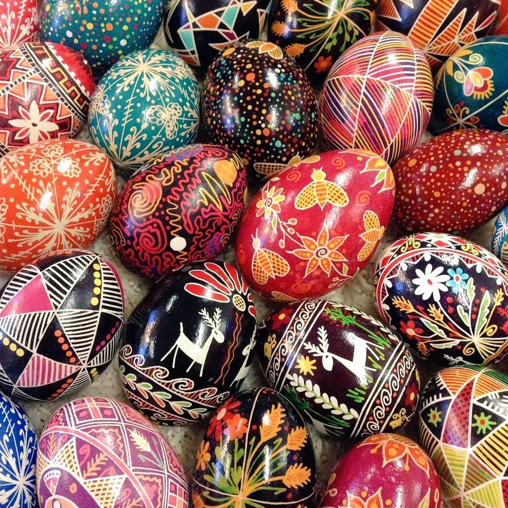 Photo of a close-up of a number of highly decorated eggs in different colours and stulised images of deer, flowers or bees as well as individuap patterns