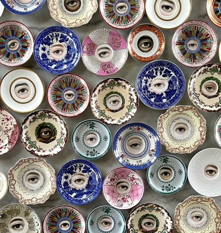 A collection of plates of similar sizes yet with different patterns and coloyrs all with an eye painted on the centre