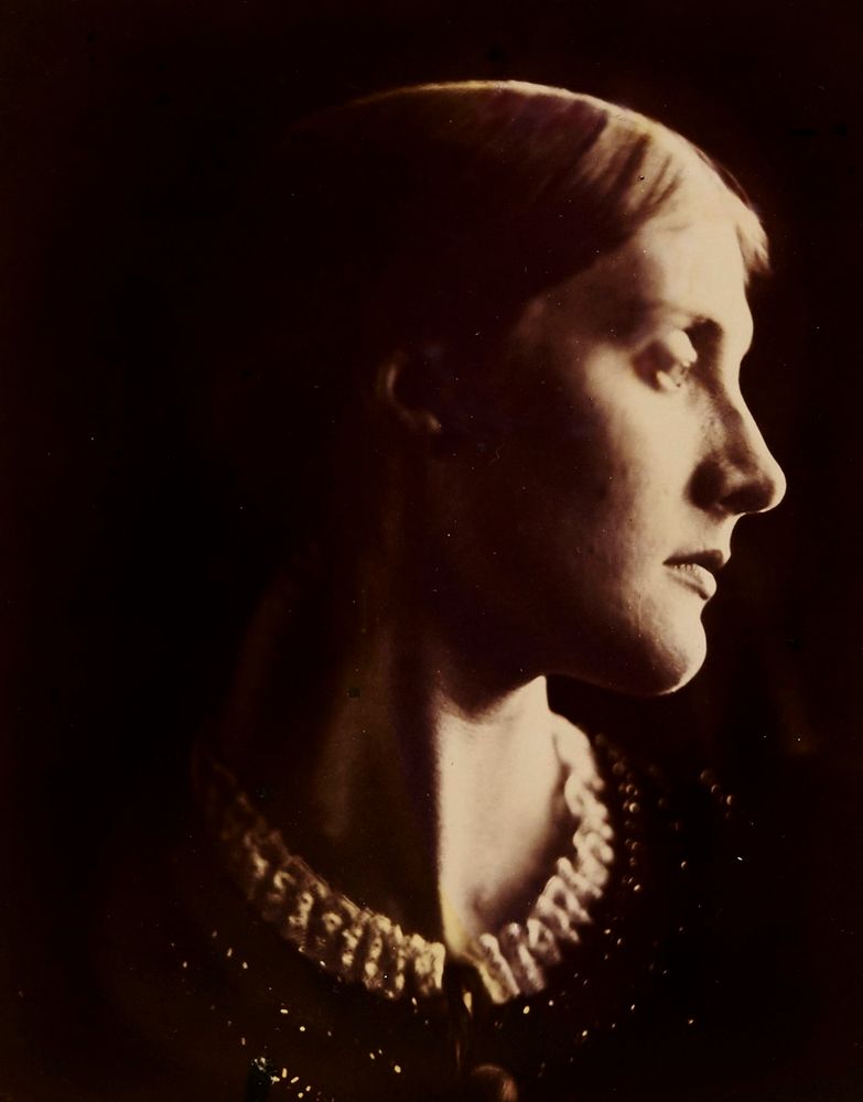 Sepia photograph of the head and shoulders of a white woman, facing forwards with head turned to face right, in half shadow