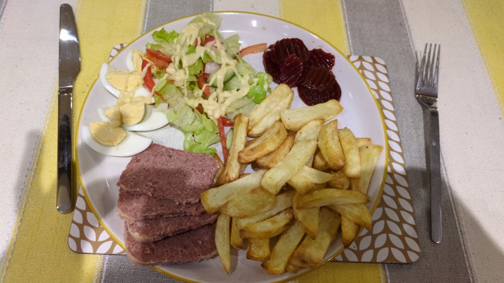 Corned beef, home made chips, boiled egg, salad and beetroot on a white plate 