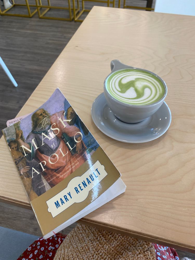 The Mask of Apollo by Mary Renault placed on a table next to a scrumptious little matcha latte.