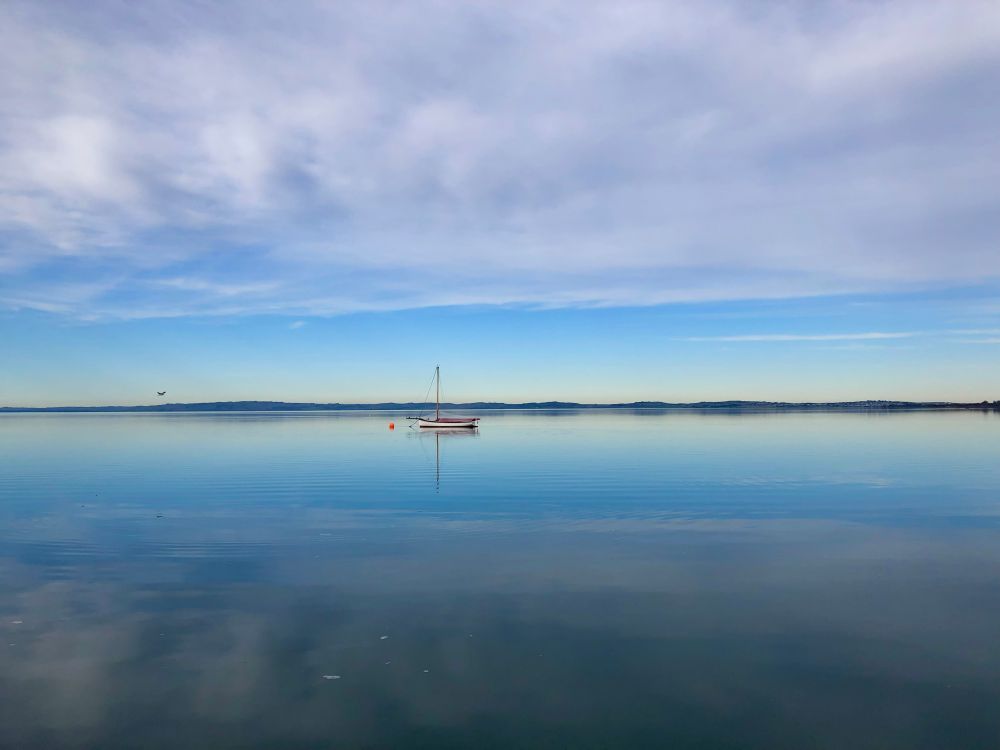 Somedays you get moments of stillness that are so complete that if you stop moving forwards you’d think that the entire world had come to a stop.
Enjoy your Sunday take time to find the still 💙
My image taken at Rhyll where the sky above has a break of blue then streaky white clouds above so that it looks like horizontal lines of colours which is also reflected in the completely still water below which has a small sail boat anchored on the water and an orange buoy off to one side.
#Stunday #Australia #Winter #photography #landscape 
#EastCoastKin #writer #PhotographersOfBluesky #sky #water #beautiful 