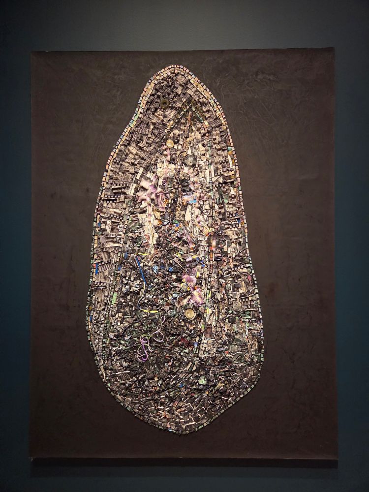 Jack Whitten painting, a tribute to WEB DuBois. An oblong shape on a dark brown background, filled with a mosaic of colors and textures created out of manipulated acrylic paint. 