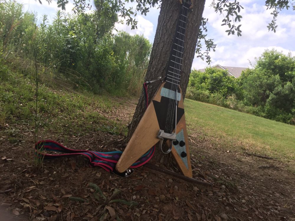 A fake flying-v style guitar painted to resemble the Triforce. Or more accurately the guitar in that modern beta design for BOTW Link. The guitar is strung with real pegs, a faked horseshoe bridge, no pickups, a nonexistent scratchboard, and a whammy bar.

When making this back in 2018, my Mom affectionately referred to it and the design that was the baseline of most of the choices made about this piece: as 'the frankenguitar'. She was not wrong.