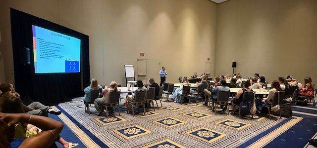 CHDI's Jason Lang stands at the front of a training room before a group of 25-30 professionals during trauma screening workshop