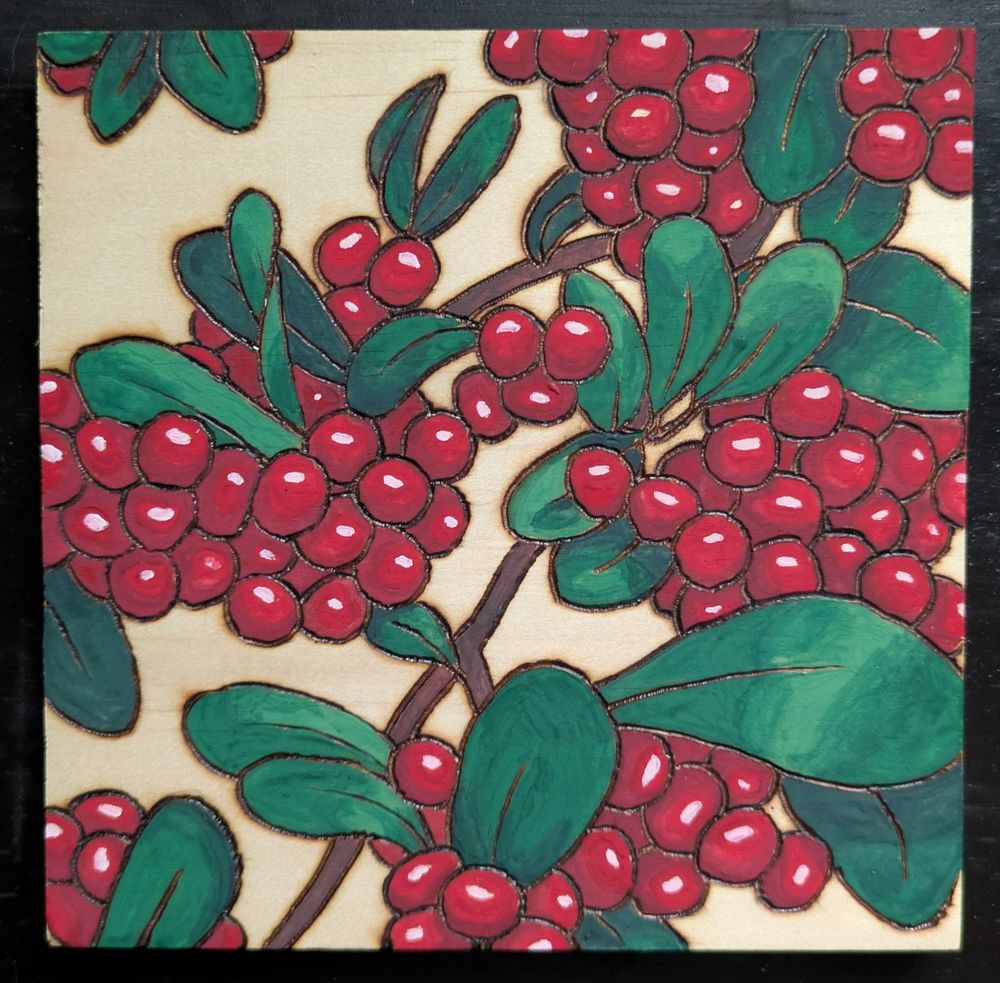 A wood panel burned with a pyrography pen and painted with watercolors to show bright red berries and lush green leaves.