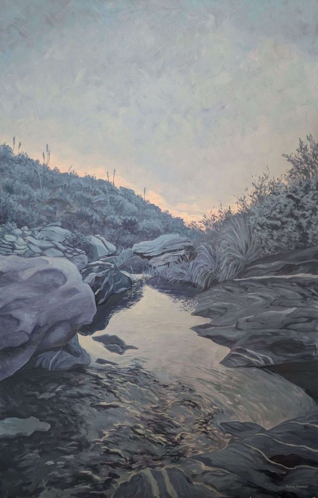 An oil painting of sunrise over a desert stream. The majority of the painting is muted purples, with the light of dawn emerging as a pale yellow reflected in the water.