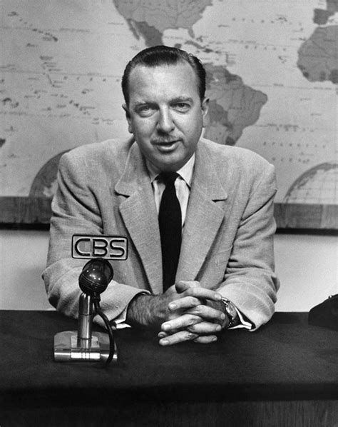 Walter Cronkite sitting at news desk with a CBS microphone in front of him. 