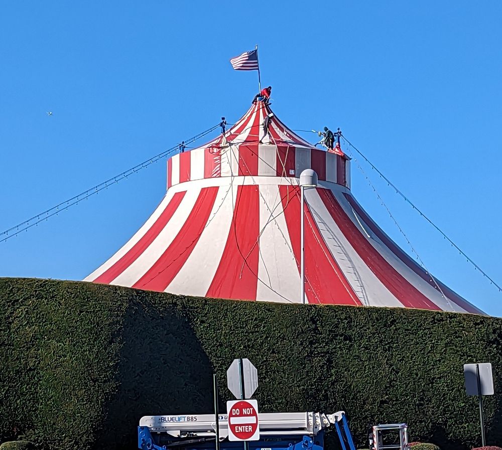 Men planting the American flag atop a circus tent. Bx NY. 