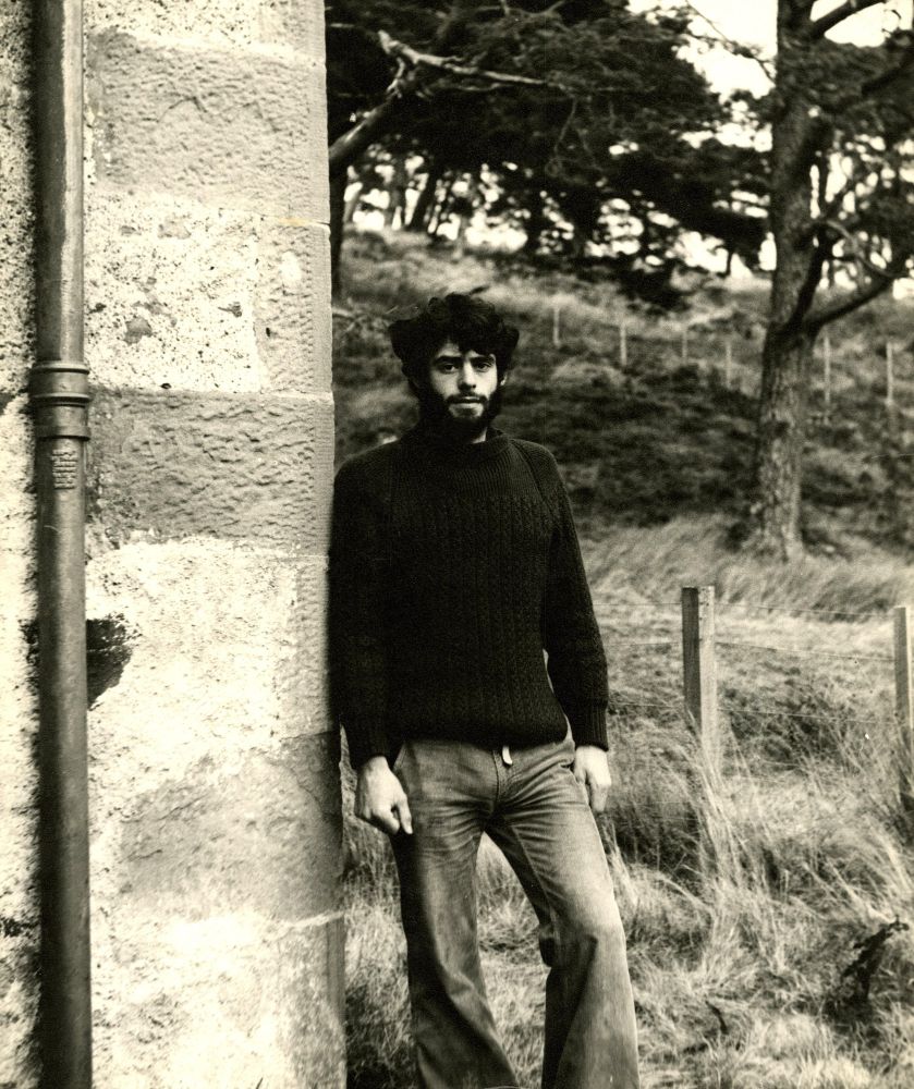 A black and white photograph of Mark Beeson leaning against a wall. Copyright held by Mark Beeson's children.