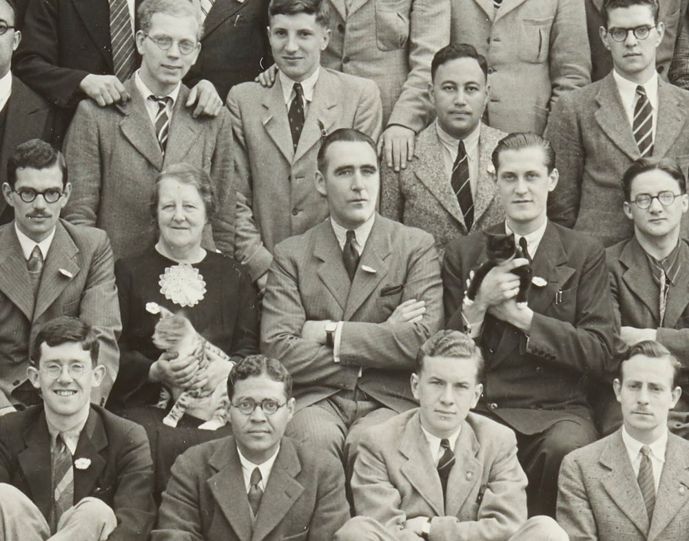 Cropped version of the first photograph, focusing on the matron, warden and president in the centre of the group. The matron is holding a light-coloured adult cat on her lap and the president is holding a small black kitten with white socks.