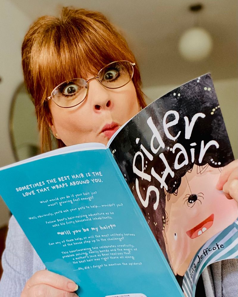 Author Laura Jeffcote holding a copy of Spider Hair