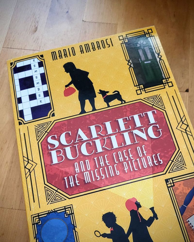 Photo of a copy of Scarlett Buckling and the Case of the Missing Pictures on a wooden table.