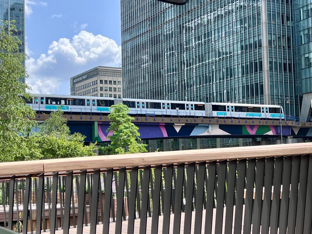 New DLR train passing on bridge between Canary Wharf and Heron Quays stations in the summer sunshine. 