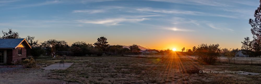 Sunrise panorama with the sun at the right third and a few white clouds
