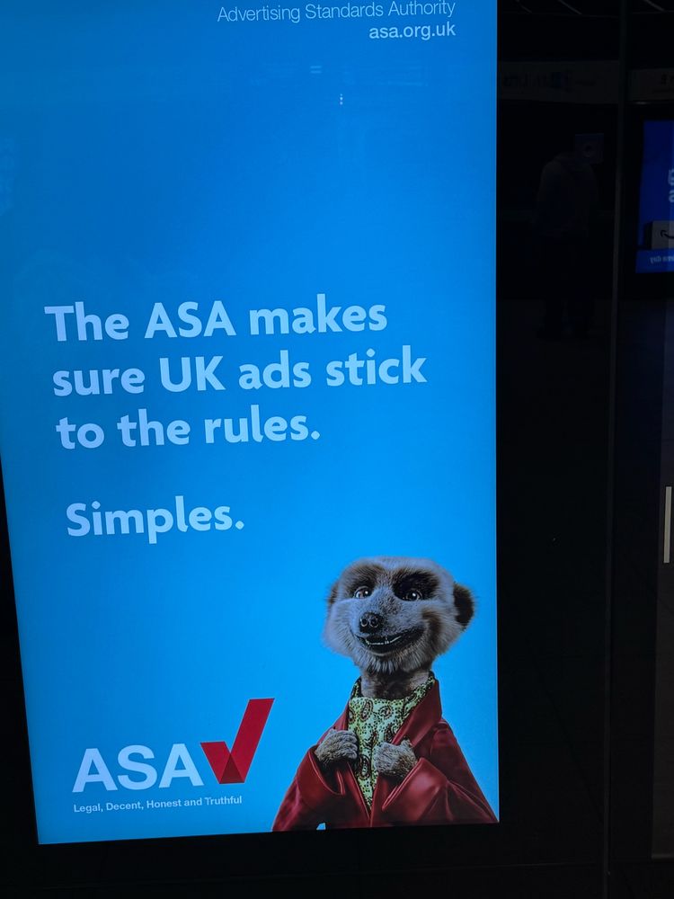 Advertising board. THE ASA MAKES SURE UK ADS STICK TO THE RULES, it says, against a blue backdrop. SIMPLES. And there is that meerkat from ten years of tv adverts.