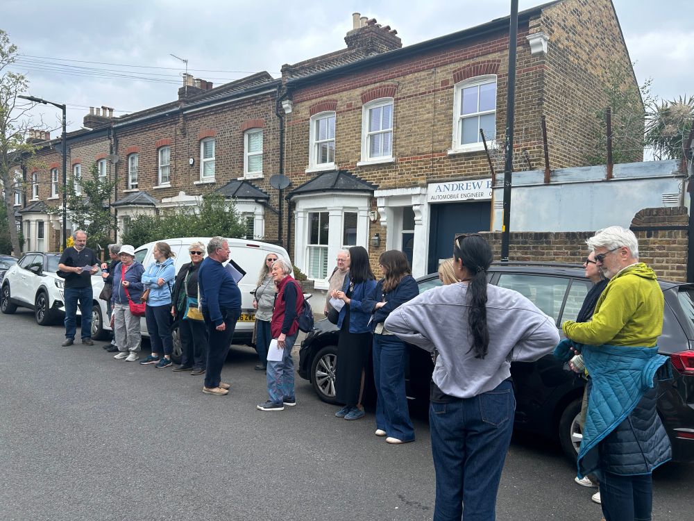 People stand in a street looking at Victorian houses