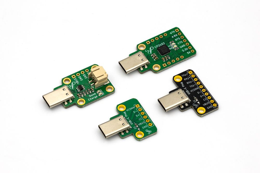 a photo of four boards. two are simple breakout boards for the USB type-c plug, one has USB 3 pins, the other doesn't. the other two boards are also USB type-c plug ones, but one has a battery charger chip and connector, and the other one has a cp2102 serial chip and footprints for headers.