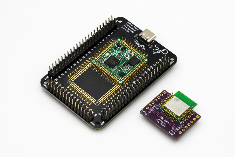 A photo of two development boards. One is a board with a Stamp footprint and a stamp held down by flexypins. the board has double row pin headers all around the stamp and a USB port. the other board is a simple breakout with the RPi RM2 held by flexypins