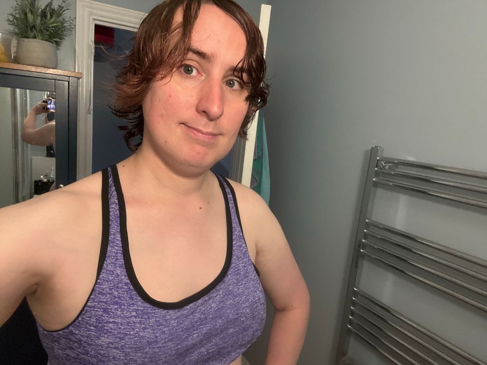 Ruby smiles, her hair still frizzy and wet after a fresh wash in the bath. she's wearing a purple sports bra