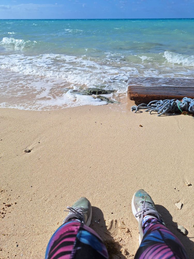 POV of beach, sneakers and leggings in view.